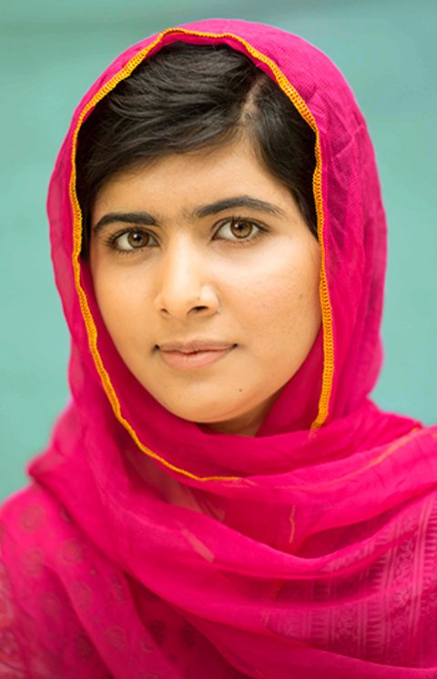 Malala Yousafzai é uma escritora paquistanesa cuja a pele é clara, cabelos escuros, muito lisos e olhos cor de mel. Na imagem ela está vestida com hijab rosa, cobrindo cabeça e pescoço.