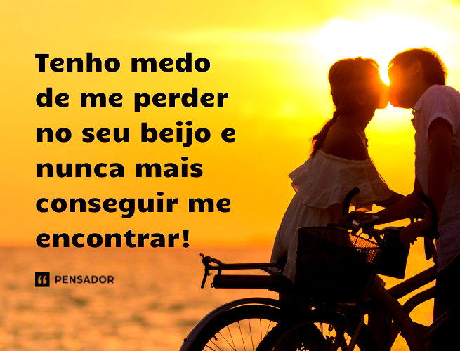 Casal se beijando em cima de suas bicicletas em frente ao mar.