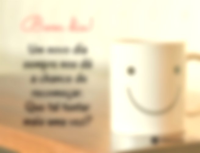 Xícara de café com o desenho de uma carinha feliz em cima de uma mesa.